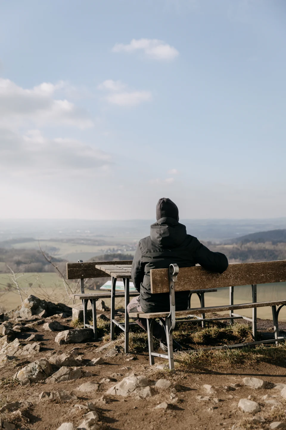 Muž sedící na lavičce hledící do krajiny